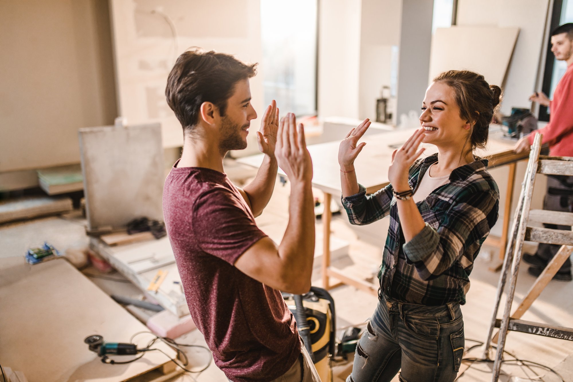 Happy young couple, looking at eachother high fiving in an indoor DIY environment