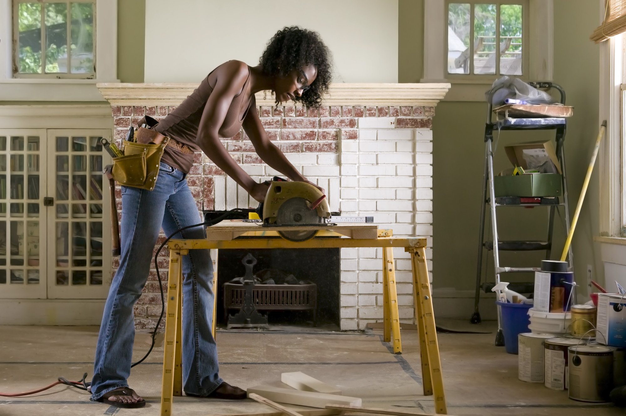 Woman using a rented electric saw to cut wood for home renovations